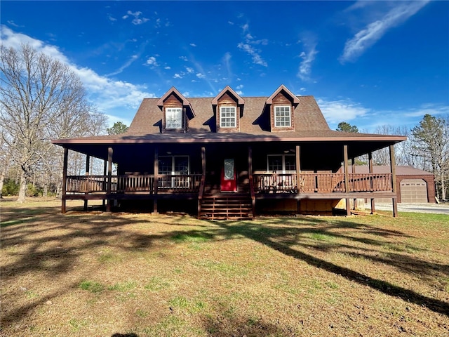 farmhouse inspired home featuring a porch, a front lawn, an outdoor structure, and a shingled roof