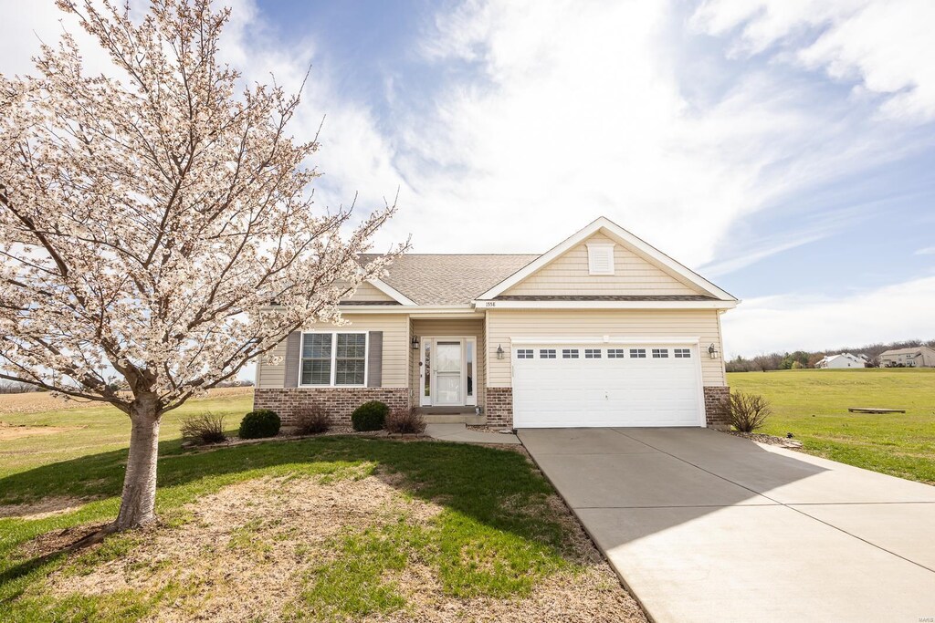 view of front of home featuring brick siding, a garage, concrete driveway, and a front yard