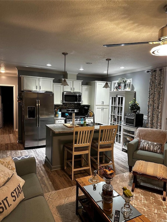 living area featuring recessed lighting, ornamental molding, a textured ceiling, and wood finished floors
