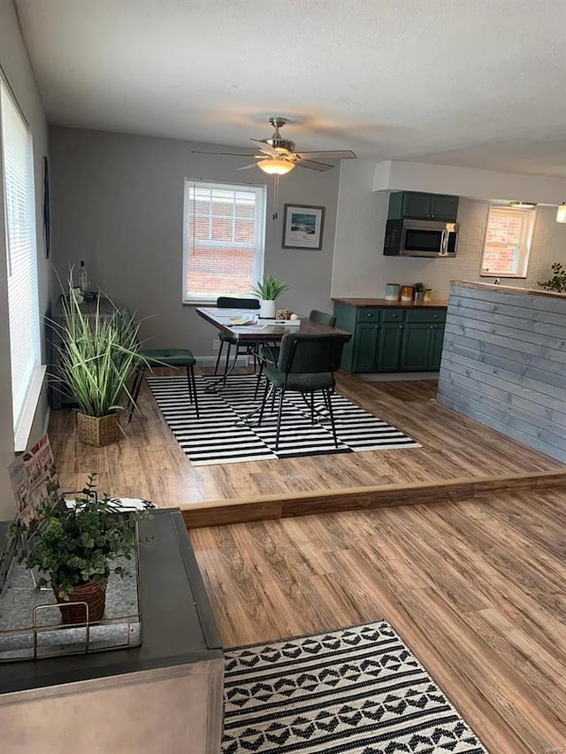 dining space featuring a ceiling fan, wood finished floors, and a textured ceiling