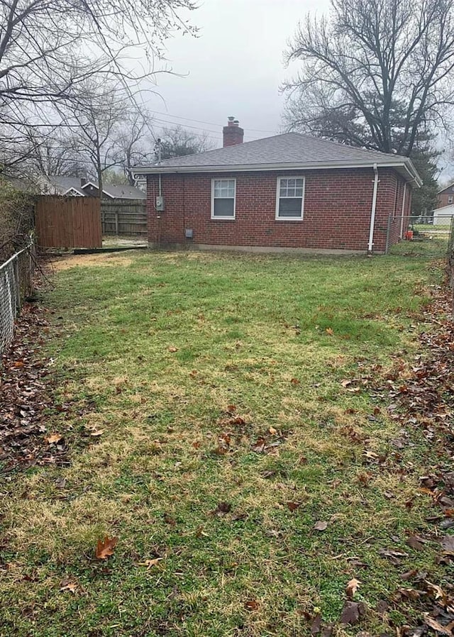 exterior space with brick siding, a lawn, fence private yard, and a chimney