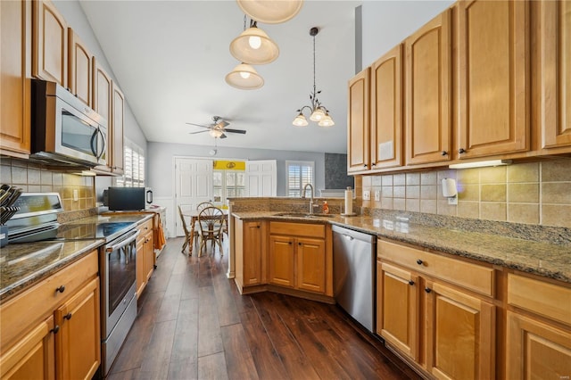 kitchen featuring ceiling fan, a sink, stone countertops, dark wood-style floors, and stainless steel appliances