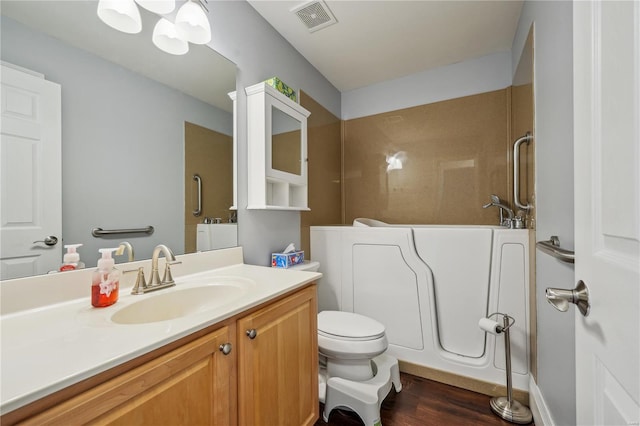 full bathroom with visible vents, vanity, wood finished floors, toilet, and walk in shower