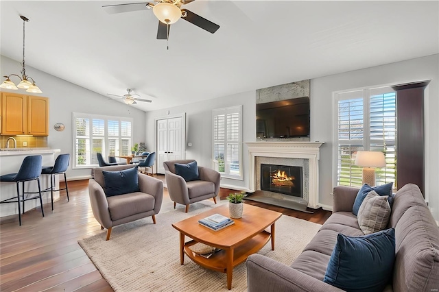 living room with ceiling fan, light wood finished floors, lofted ceiling, and a high end fireplace