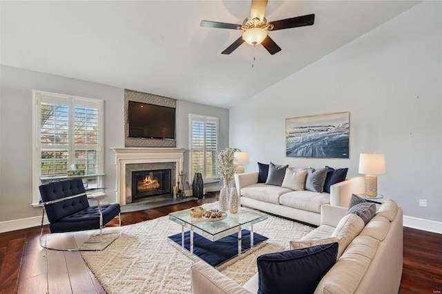 living room with a ceiling fan, baseboards, dark wood-style floors, lofted ceiling, and a glass covered fireplace