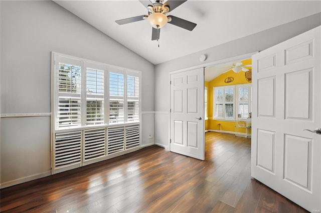 interior space with dark wood-style flooring, a ceiling fan, baseboards, and vaulted ceiling
