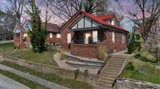 tudor house featuring brick siding, fence, stairs, and a lawn