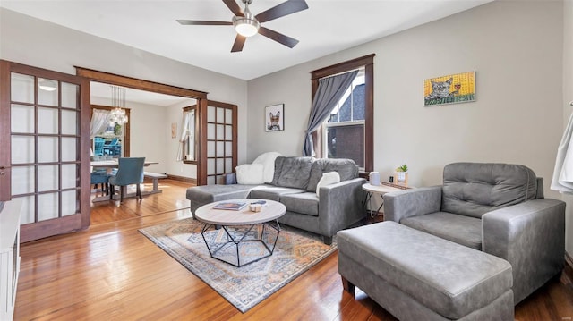 living area with baseboards, light wood-style floors, and ceiling fan with notable chandelier