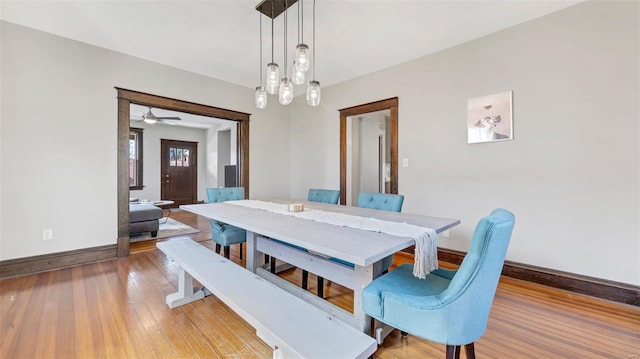 dining space with baseboards, wood finished floors, and a ceiling fan
