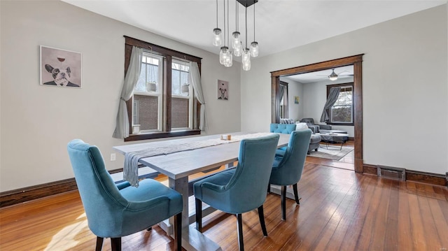 dining room with baseboards, visible vents, a ceiling fan, and wood-type flooring