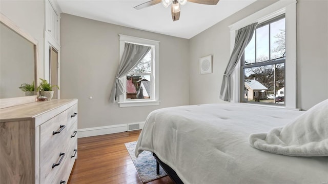 bedroom featuring baseboards, dark wood-style flooring, ceiling fan, and visible vents