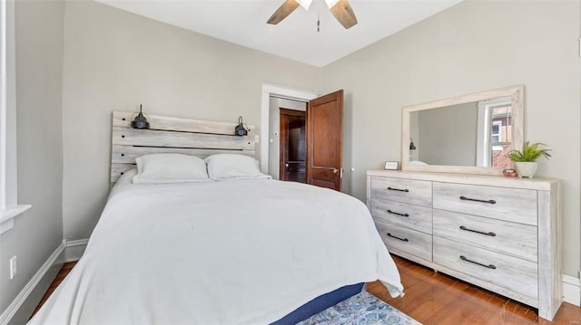 bedroom with dark wood-style floors, baseboards, and a ceiling fan