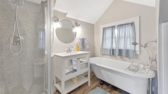 bathroom featuring a stall shower, vanity, wood finished floors, lofted ceiling, and a freestanding bath