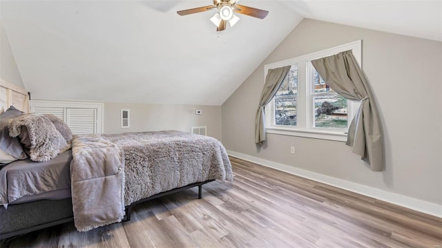 bedroom with visible vents, baseboards, wood finished floors, a ceiling fan, and vaulted ceiling