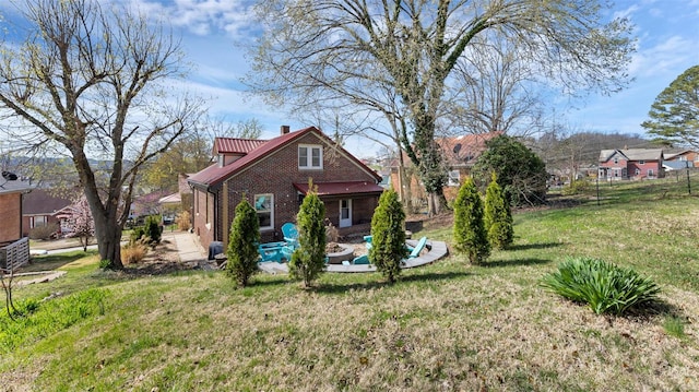 rear view of property featuring brick siding, a patio area, and a lawn