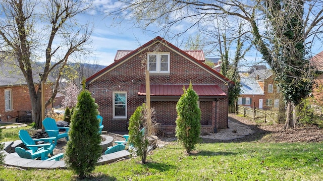 rear view of property featuring metal roof, fence, a patio, brick siding, and a yard