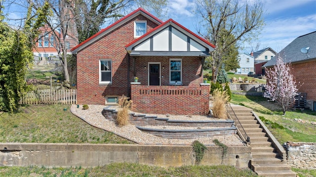 view of front of property with stairs, fence, brick siding, a front lawn, and a porch