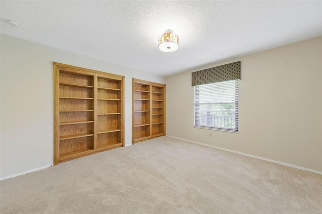 spare room with baseboards, carpet floors, a textured ceiling, and built in features