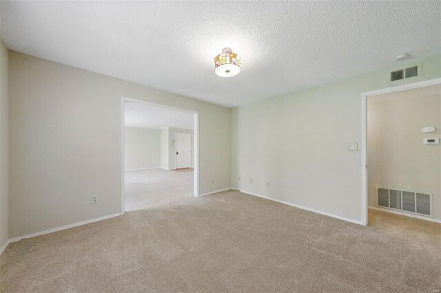 carpeted spare room with baseboards, a textured ceiling, and visible vents
