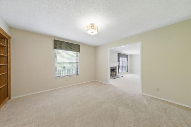 spare room with carpet floors, a fireplace with raised hearth, and plenty of natural light