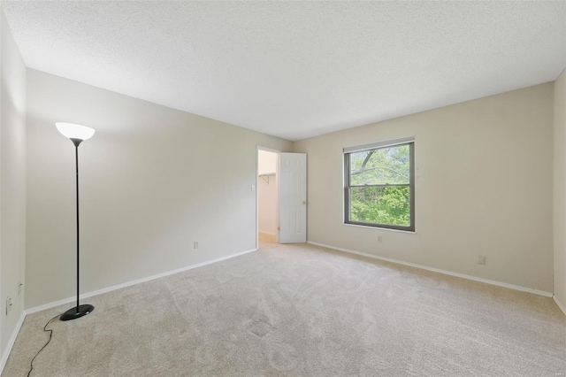 spare room with baseboards, a textured ceiling, and carpet