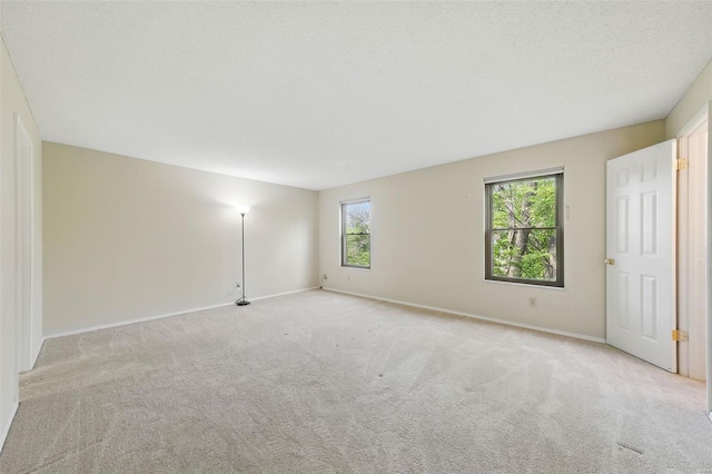 spare room featuring light colored carpet and baseboards