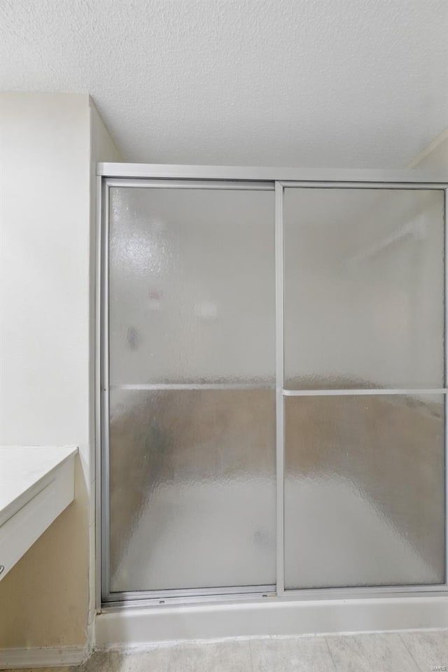 bathroom featuring vanity, a textured ceiling, and a stall shower
