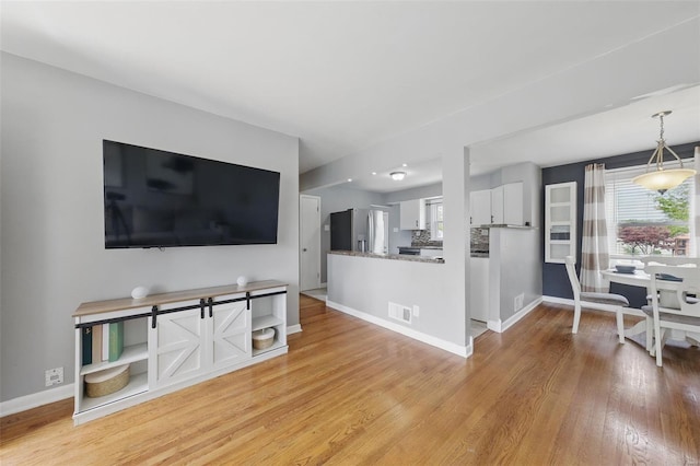 unfurnished living room featuring baseboards, visible vents, and light wood-type flooring