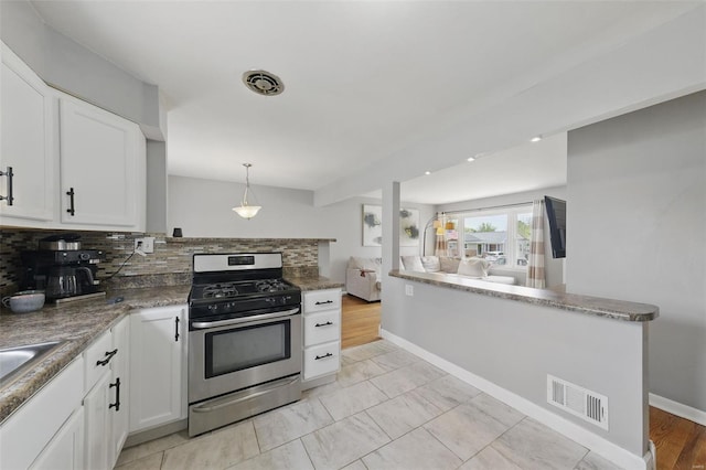 kitchen featuring tasteful backsplash, visible vents, white cabinetry, a peninsula, and gas stove
