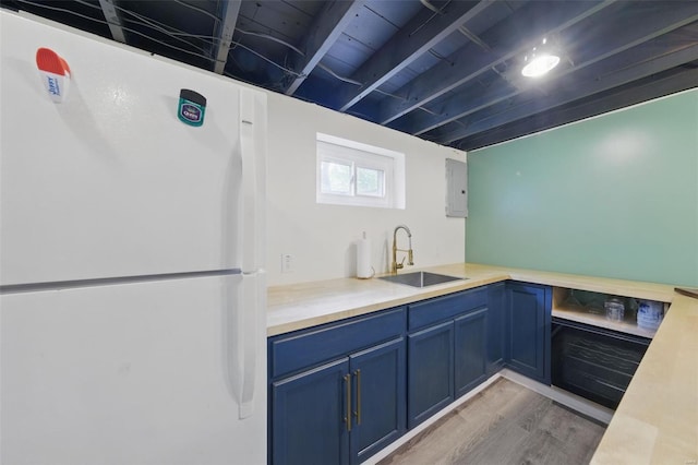 kitchen with blue cabinetry, light wood-style flooring, freestanding refrigerator, and a sink