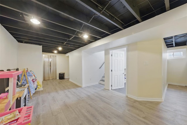 basement with baseboards, wood finished floors, and stairs