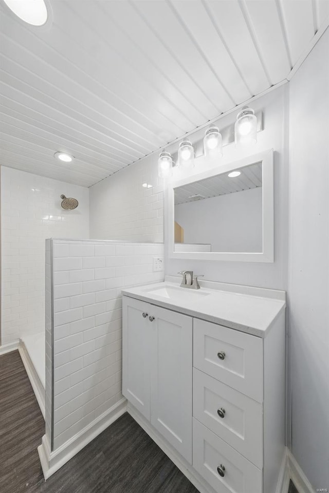 bathroom featuring a tile shower, wood finished floors, and vanity