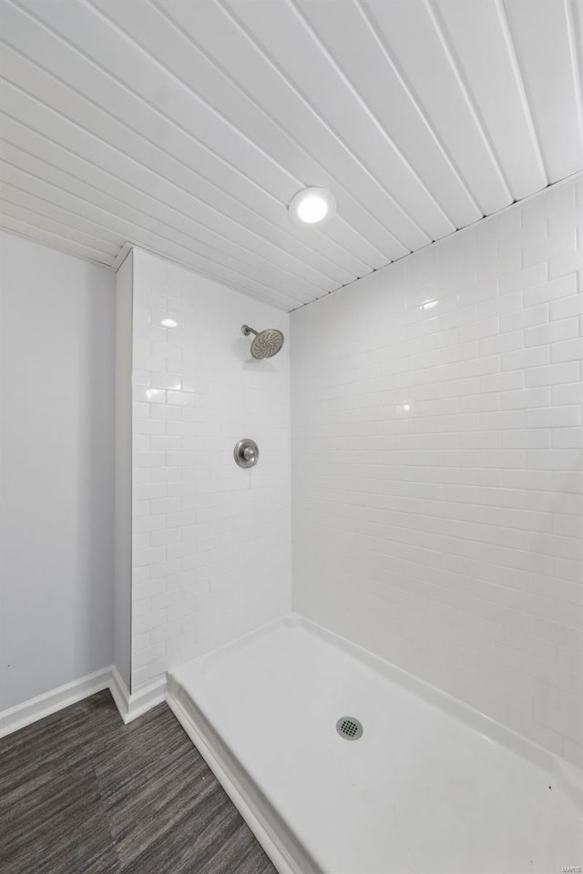 full bathroom featuring baseboards, tiled shower, and wood finished floors