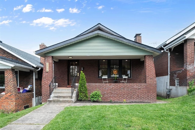 bungalow-style house featuring a porch, brick siding, a front lawn, and a chimney