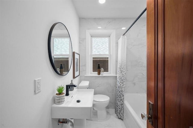 bathroom with marble finish floor, shower / bath combination with curtain, toilet, tile walls, and a sink