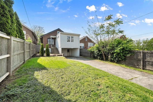 back of property featuring a fenced backyard, a yard, and stairway