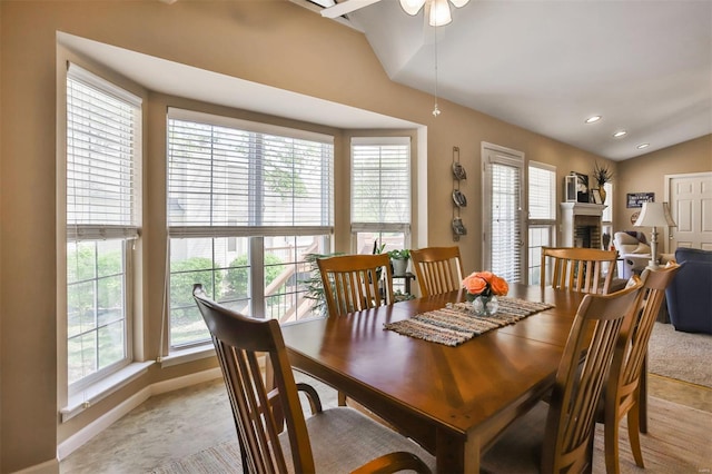 dining space with lofted ceiling, baseboards, a fireplace, and ceiling fan