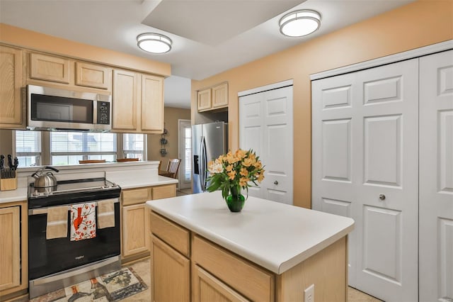 kitchen featuring a center island, stainless steel appliances, light countertops, and light brown cabinetry