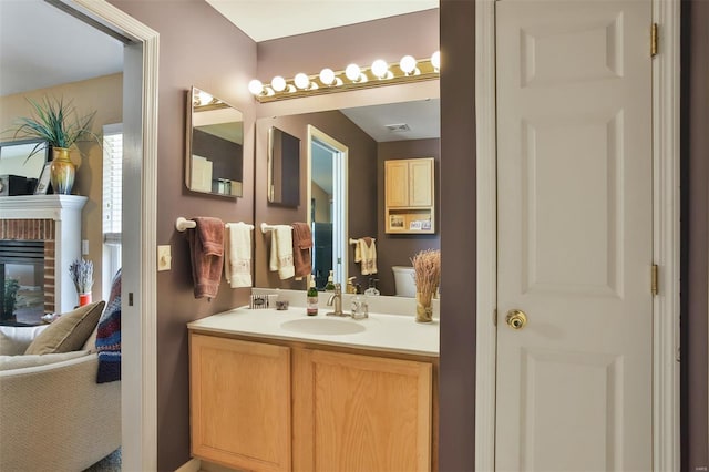 bathroom featuring visible vents, a brick fireplace, vanity, and connected bathroom