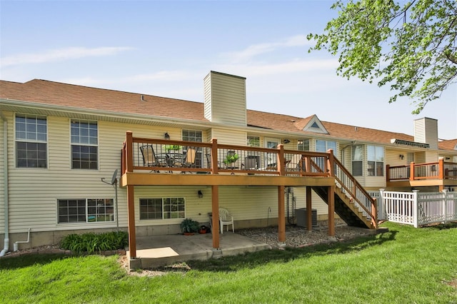 rear view of house with a lawn, a chimney, a deck, and a patio