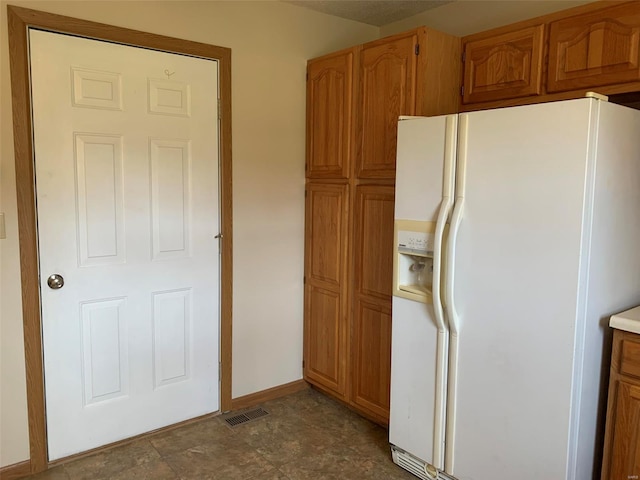 kitchen with visible vents, white refrigerator with ice dispenser, brown cabinetry, and light countertops