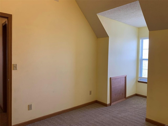 additional living space featuring vaulted ceiling, baseboards, a textured ceiling, and carpet floors