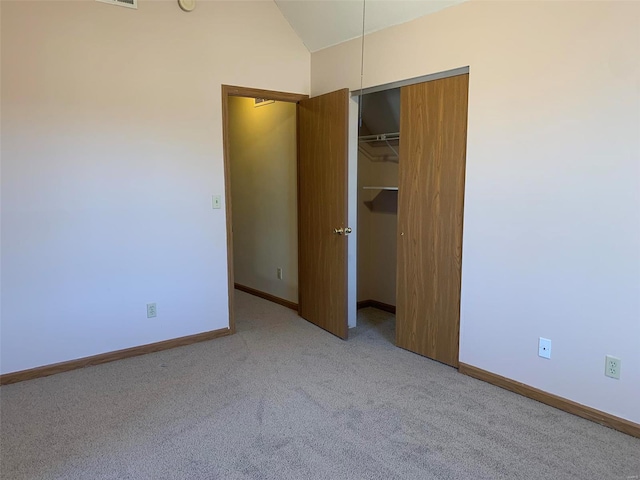 unfurnished bedroom featuring a closet, baseboards, carpet flooring, and lofted ceiling