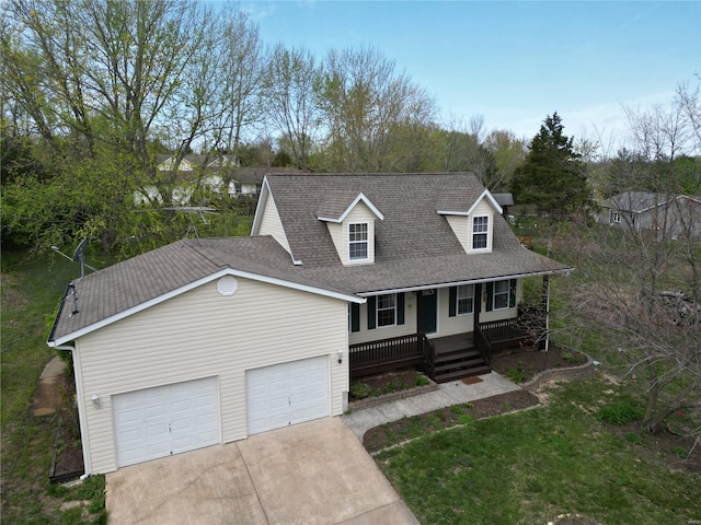 new england style home featuring a porch, a shingled roof, concrete driveway, and a garage