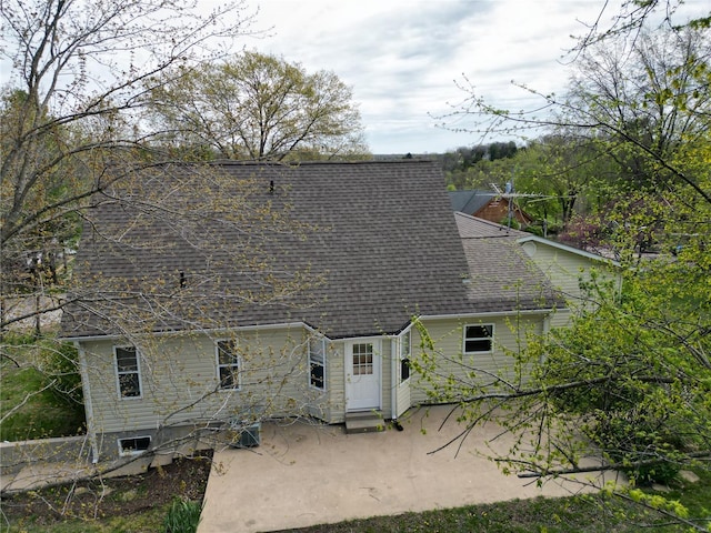back of property with a shingled roof and a patio area