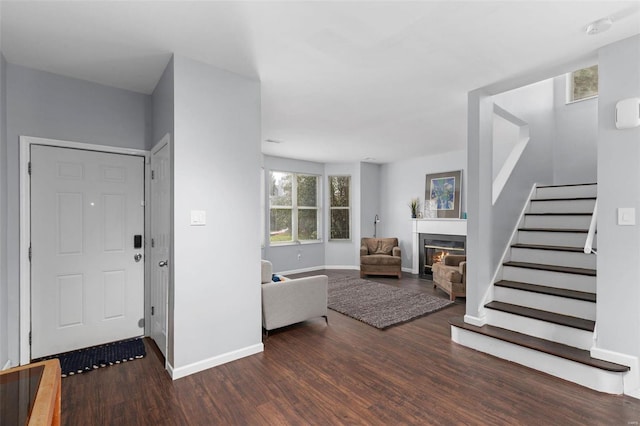 foyer with stairway, baseboards, a glass covered fireplace, and wood finished floors