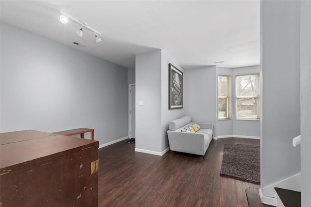 sitting room with baseboards, rail lighting, wood finished floors, and visible vents