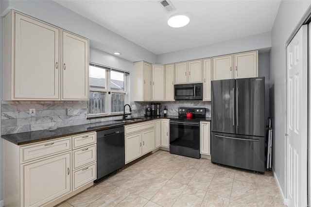 kitchen with visible vents, dark countertops, cream cabinetry, a sink, and black appliances