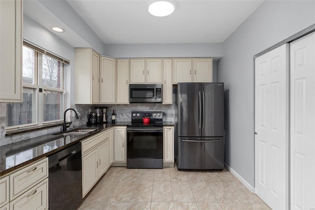 kitchen featuring a sink, baseboards, decorative backsplash, cream cabinetry, and black appliances