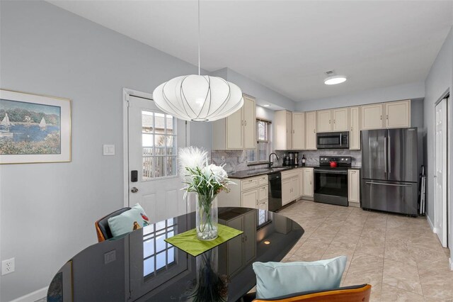 kitchen featuring a sink, backsplash, black appliances, and cream cabinets